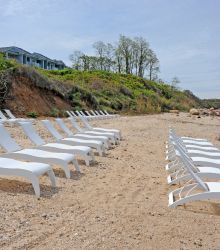 A Group Of Lawn Chairs Sitting On Top Of A Sandy Beach